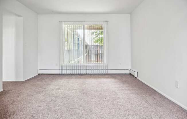 an empty living room with a large window and carpet