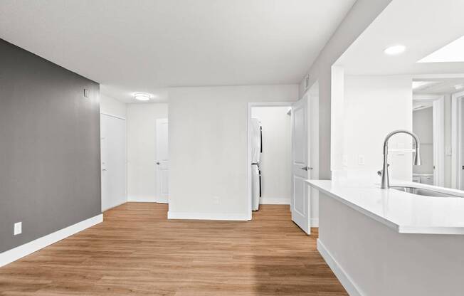 A long, narrow, white hallway with wood floors and white walls.