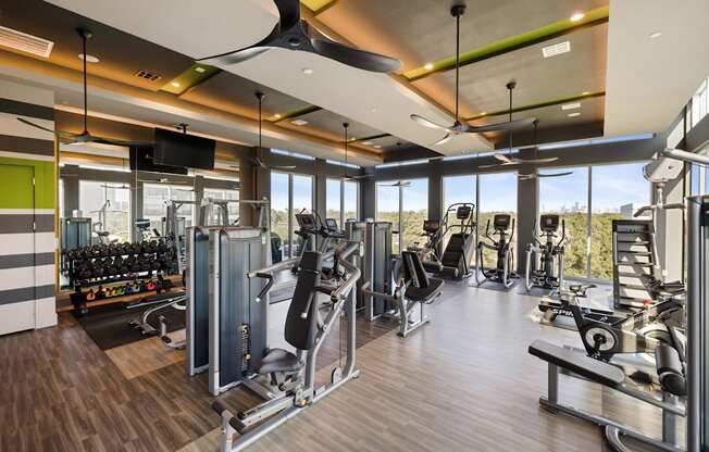A gym with a variety of equipment including treadmills, weights, and a television.