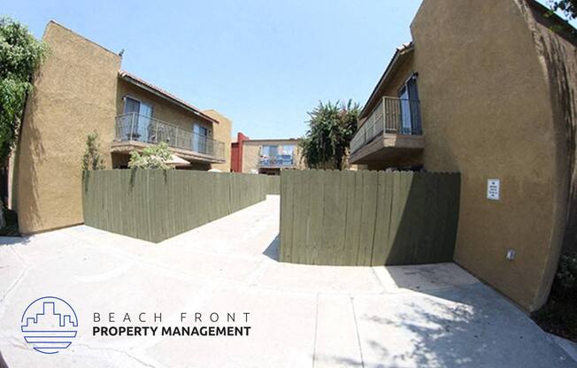 a fenced in driveway between two buildings with trees