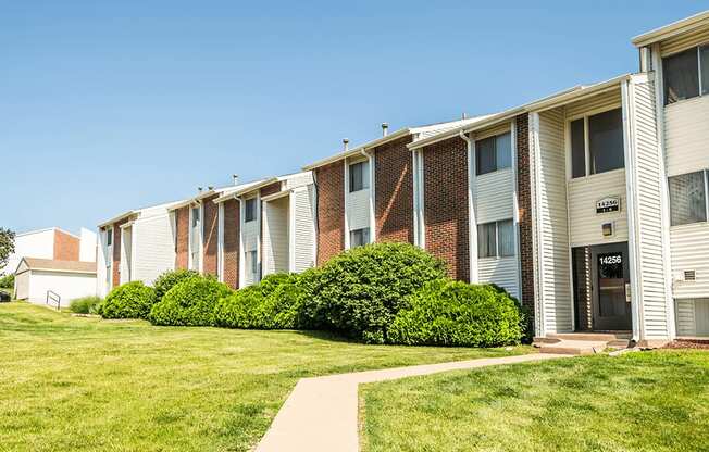 an apartment building with a green lawn and a sidewalk