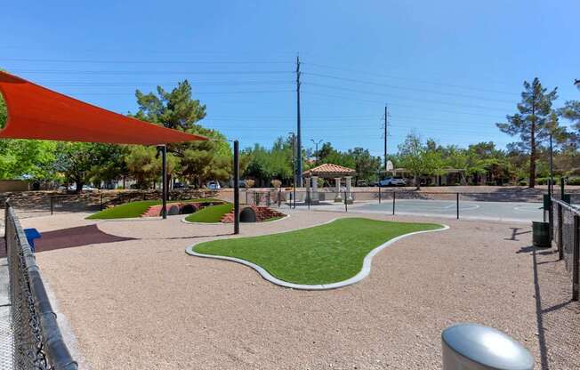 A playground with a red canopy and a gravel area.