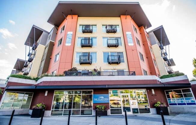 A multi-story building with a red and beige facade and balconies on the upper floors. at The Platform, Kent, 98032