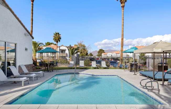 a swimming pool with lounge chairs and umbrellas at the enclave at woodbridge apartments in