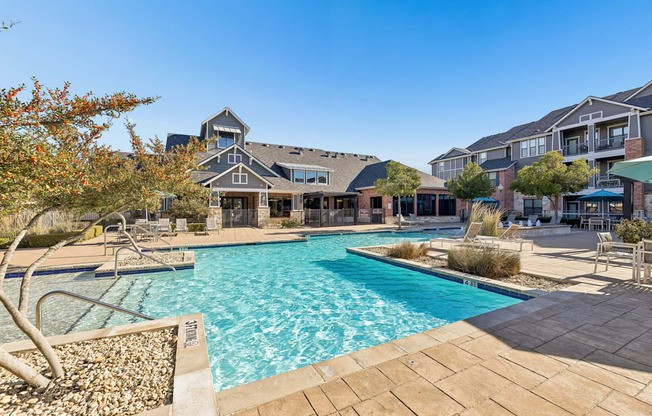 A large swimming pool surrounded by a patio and a building in the background.