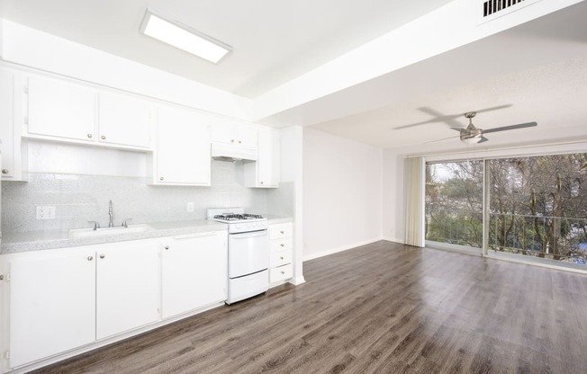 an empty kitchen with white cabinets and a ceiling fan