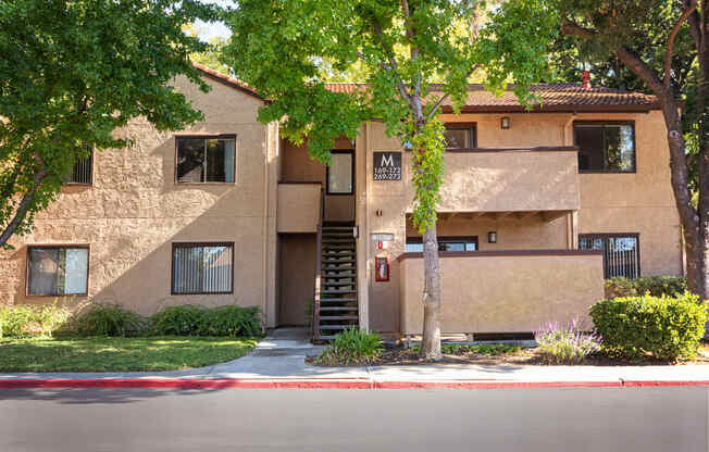 a beige apartment building with stairs and a sidewalk