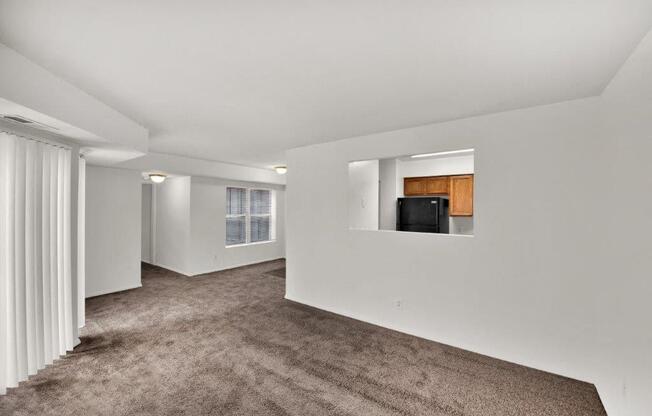 a living room with carpet and a black refrigerator