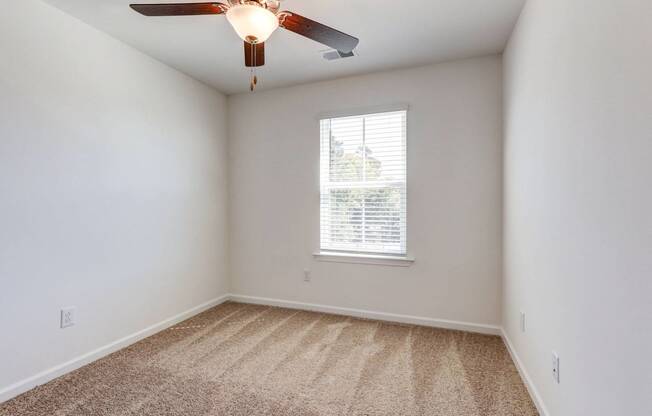 an empty room with a ceiling fan and a window
