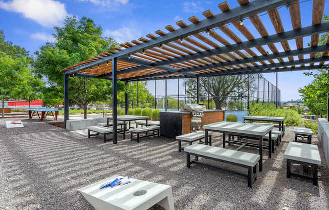 A patio with a table and chairs under a wooden pergola.