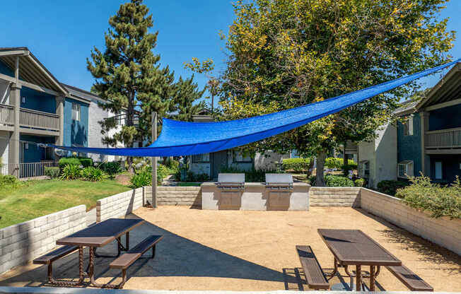A blue tarp is covering a patio area with tables and benches.