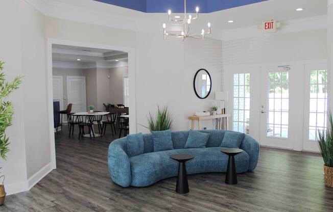A blue couch with a round mirror on the wall.