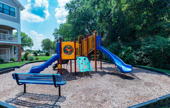 A playground with a blue slide and a yellow and red play structure.