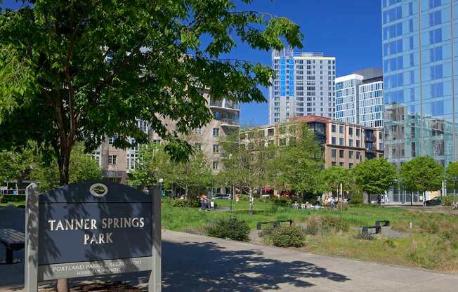 A sign that says Tanner Springs Park in front of a city park.