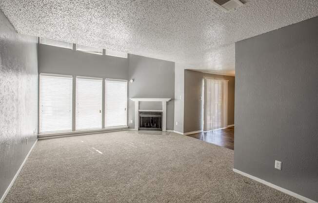 A sparsely furnished living room with a fireplace and sliding glass doors.