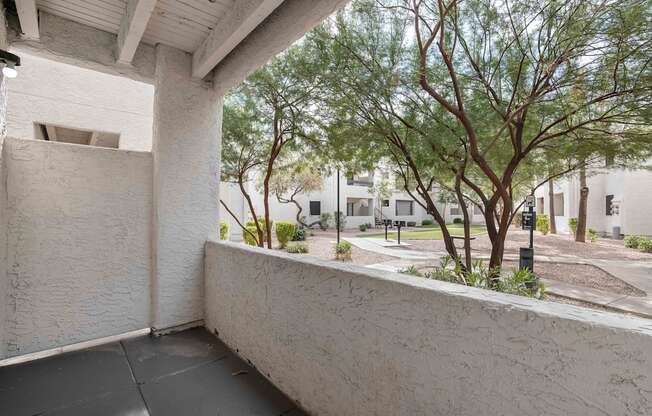 a balcony with a concrete wall and trees