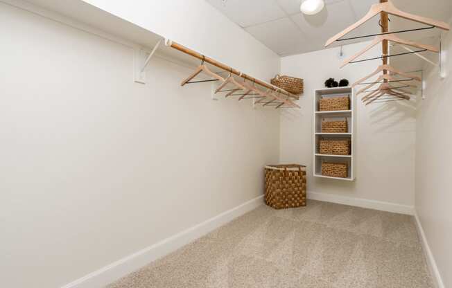 a walk in closet with shelves and a basket on the floor