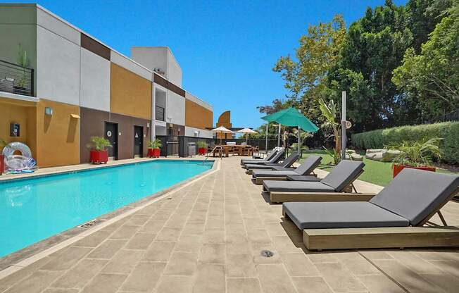 A pool with sun loungers in front of a building.