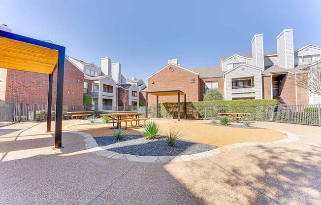 A playground area with a yellow and blue structure and benches surrounded by houses.