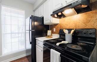 a kitchen with black appliances and white cabinets and a window