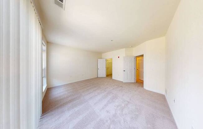 A room with a carpeted floor and two doors.