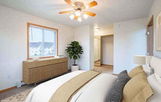 A bedroom with a large bed and a ceiling fan. Fargo, ND Summit Point Apartments