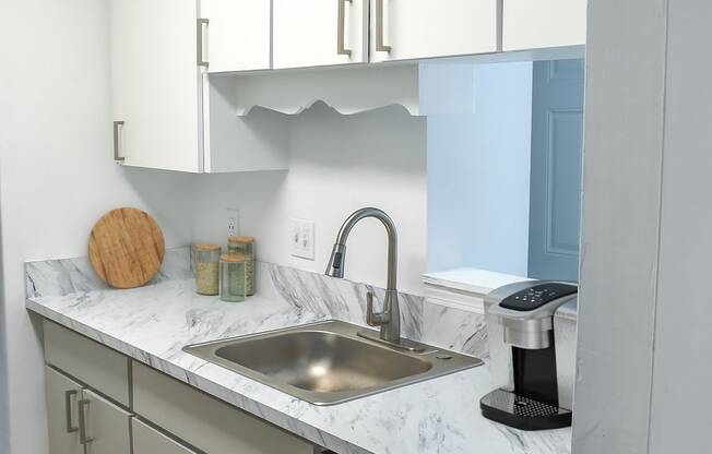 a kitchen with white cabinets and a stainless steel sink