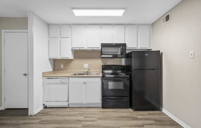 a kitchen with white cabinets and black appliances and a refrigerator at Brookside Apartments, Hewitt, TX