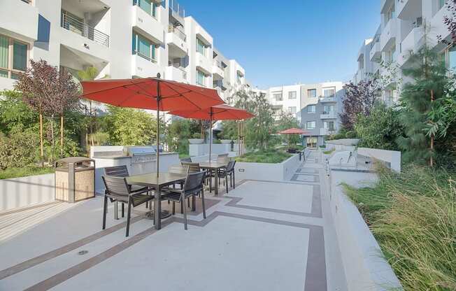 A patio with a table and chairs under a red umbrella at Woodley Sara Apartment, Van Nuys