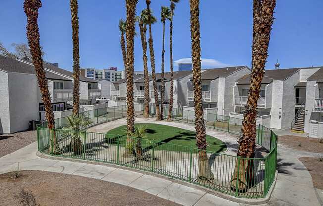 a courtyard with a green grassy area and palm trees