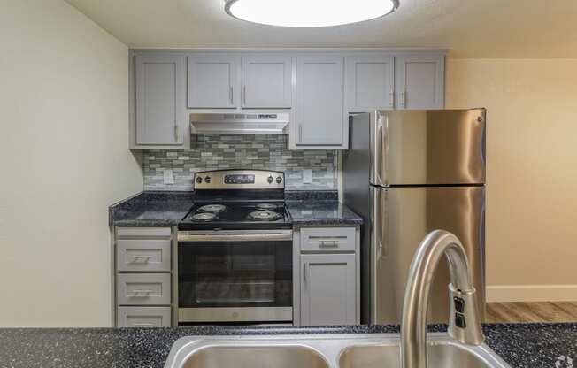 a kitchen with grey cabinets and stainless steel appliances