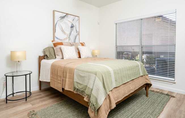 A bedroom with a bed, a lamp, and a painting on the wall.