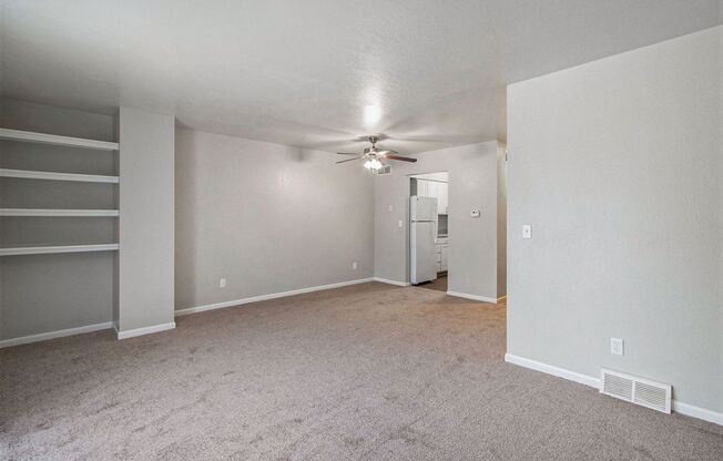 an empty living room with carpet and a ceiling fan
