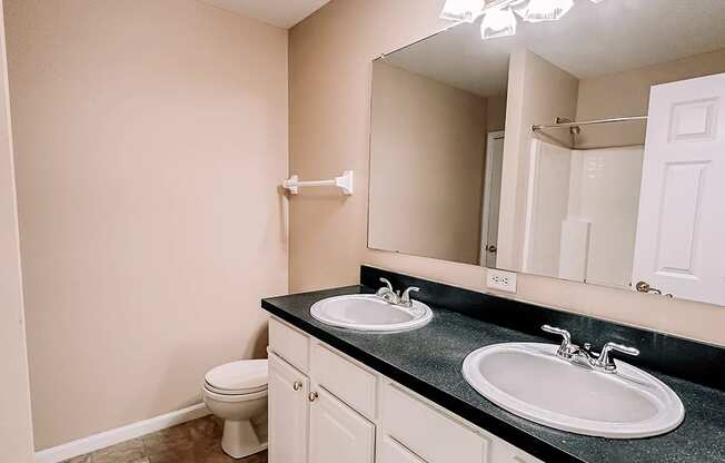 an empty bathroom with two sinks and a toilet