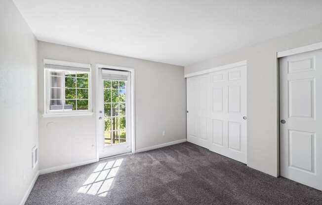 an empty living room with white walls and doors and carpet