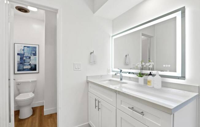 a white bathroom with a large mirror and a toilet