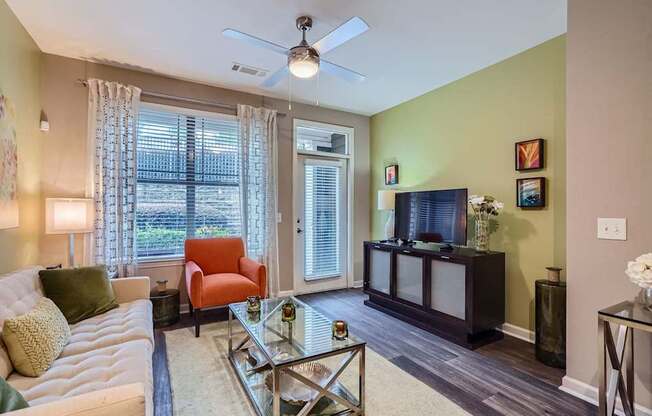 A living room with a white couch, a red chair, and a glass coffee table.