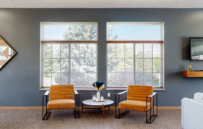 clubhouse living room with two orange chairs and a white coffee table in front of two large windows