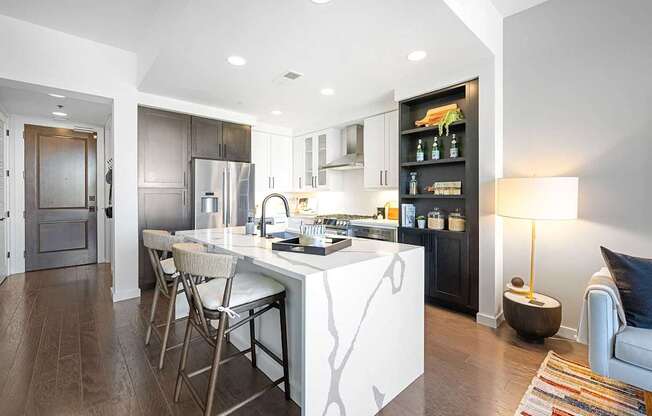 A modern kitchen with a white island and dark wood floors.