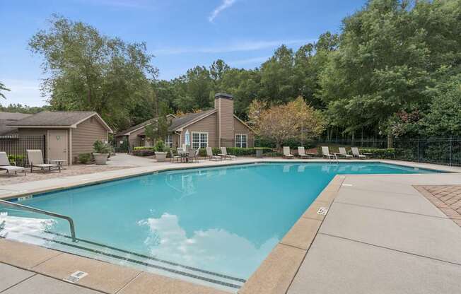 A swimming pool surrounded by trees and a house.