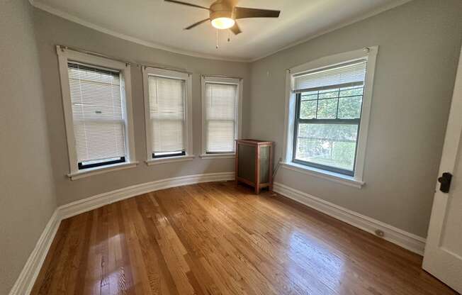 an empty living room with wood floors and a ceiling fan