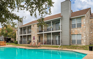 our apartments offer a swimming pool and a patio with lounge chairs at The Broadwater at Salado Creek, San Antonio, TX