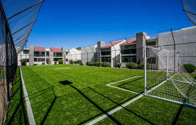 a soccer goal on a field in front of an apartment building