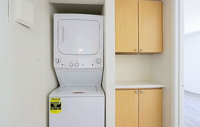 A white dishwasher is in a kitchen next to a wooden cabinet.