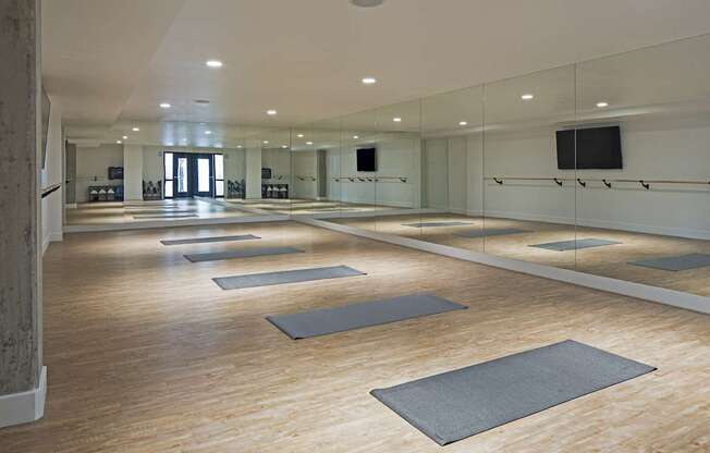 A yoga studio with wooden floors and mirrors on the wall.