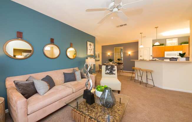 a living room with a blue accent wall and a tan couch