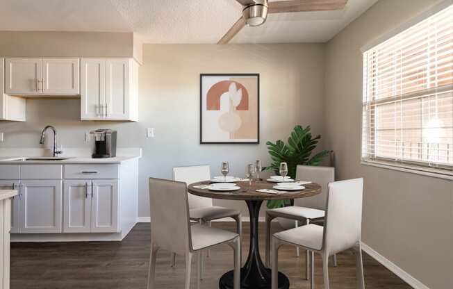 Renovated kitchen with white cabinetry, laminate countertop, and wood-style plank flooring at Acacia Gardens, Albuquerque, New Mexico