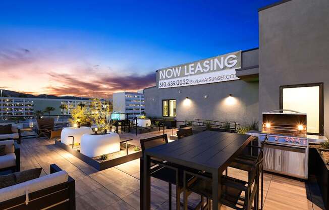 A rooftop patio with a table and chairs and a grill.