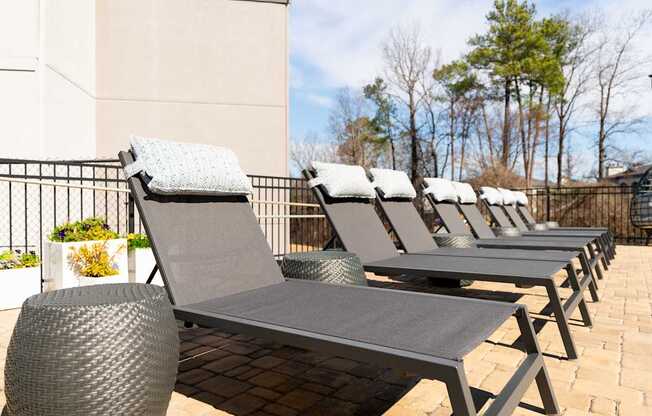 a row of gray lounge chairs on a brick patio