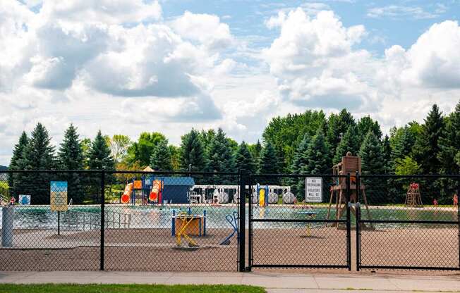 A playground with a fence and a sign in the background.